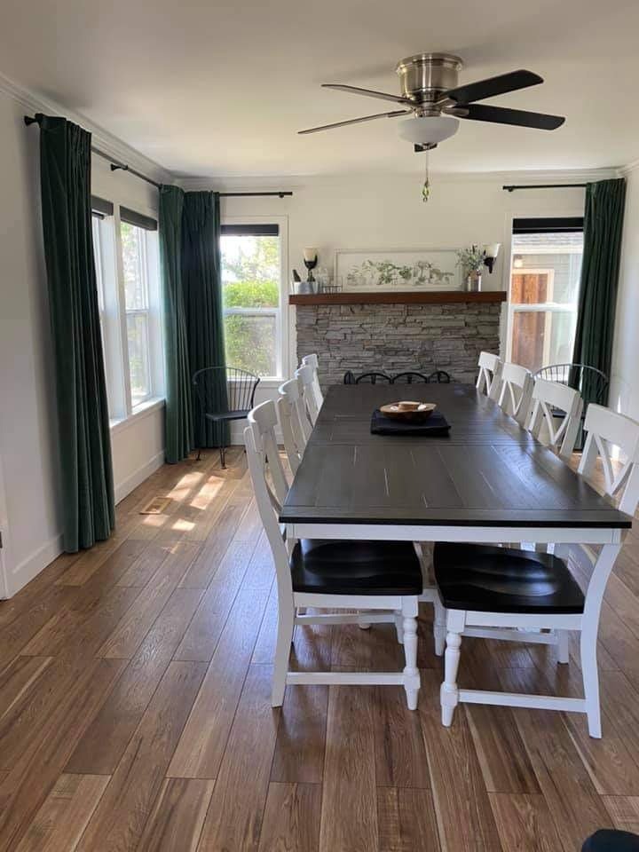 Dining area with warranty-covered drapery panels framing large, sunlit windows.