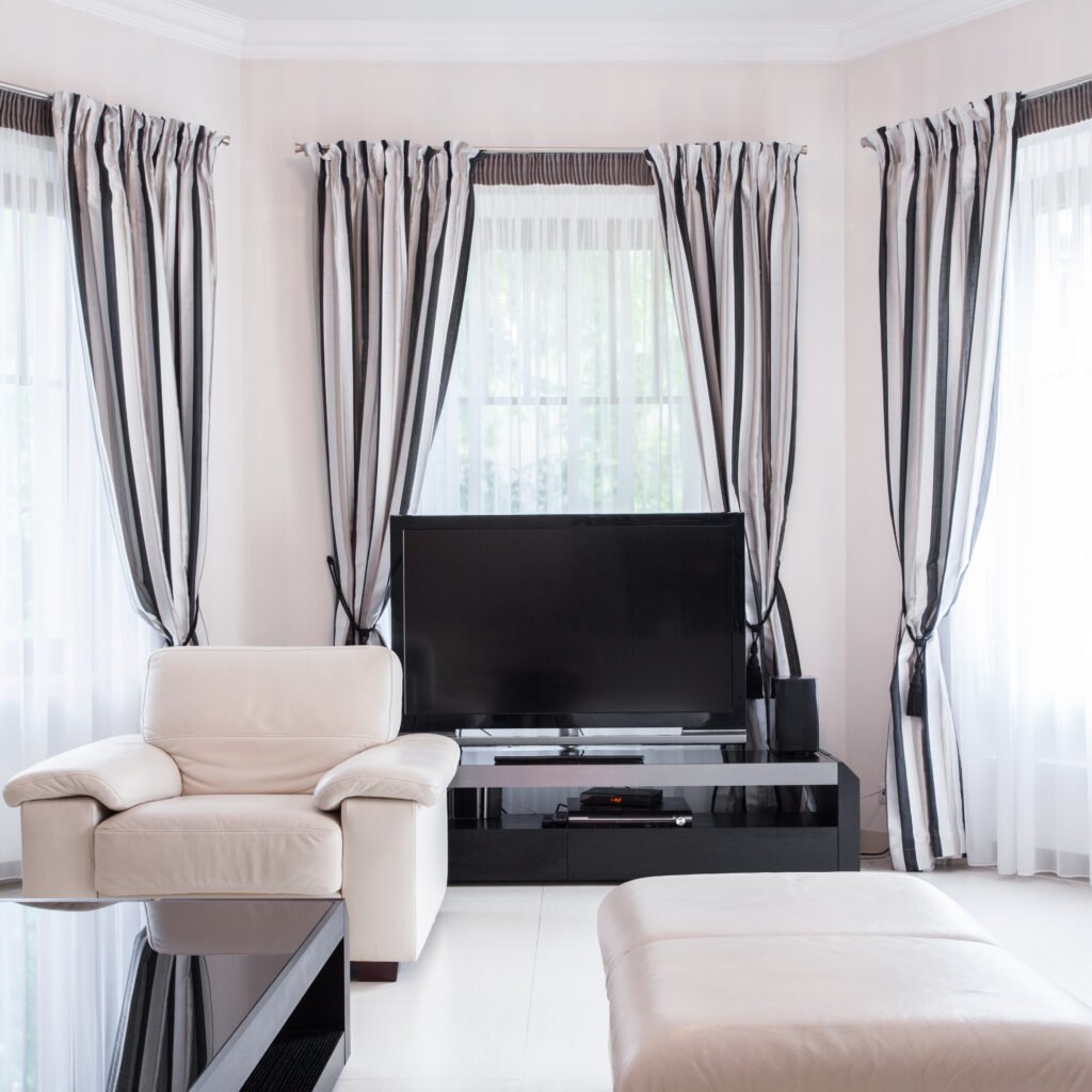 Modern living room with striped curtains, showcasing current drapery trends.